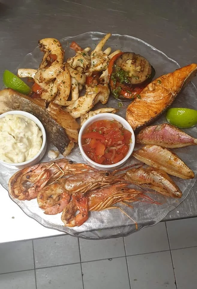 Plateau de poissons et fruits de mer avec crevettes, légumes, citron vert et sauces.